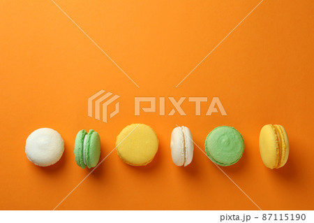 Concept of tasty dessert with macarons on orange background Concept of tasty dessert with macarons on orange background 87115190