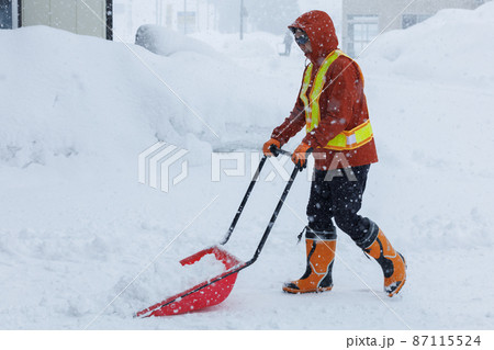 冬に雪寄せ作業をしている男性　スノーダンプ 87115524