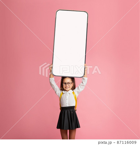 Little school girl showing white empty smartphone screen Little school girl showing white empty smartphone screen 87116009