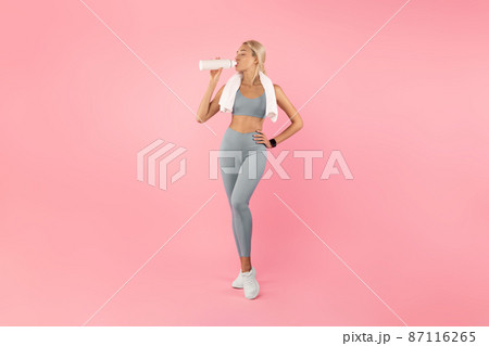 Sporty woman drinking water from bottle after exercising Sporty woman drinking water from bottle after exercising 87116265
