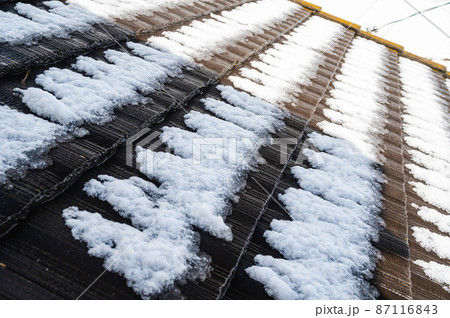 溶け始めた屋根の雪の写真素材