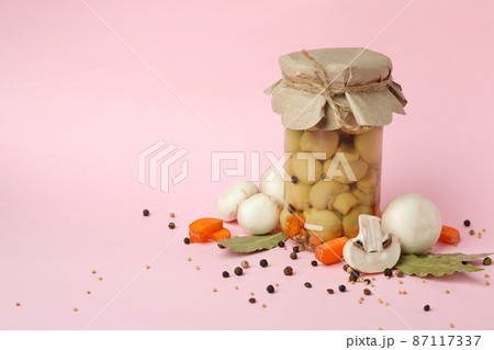 Jar with marinated mushrooms on pink background 87117337