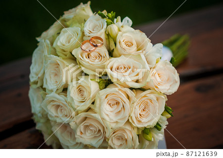 Wedding gold rings on a bouquet with white roses Wedding gold rings on a bouquet with white roses 87121639