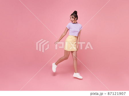 Happy Asian woman smiling and  Jumping like running while her looking back at pink copy space background. 87121907