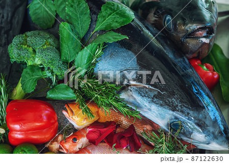 fresh and marinated fish ready for grilling, decorated with herbs and vegetables 87122630