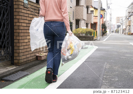両手でゴミ袋を持つ女性 87123412