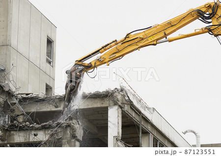 老朽化した公共建造物の解体作業をする重機 87123551