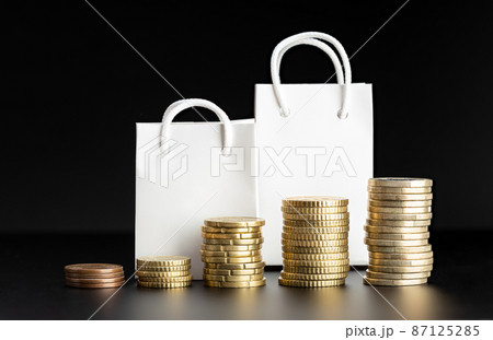 Rising coins and blank shopping bags on black background. Rising prices or inflation concept. Mock up 87125285