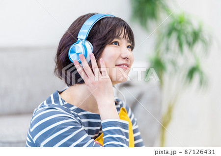 ヘッドフォンで音楽を聴く若い女性 87126431