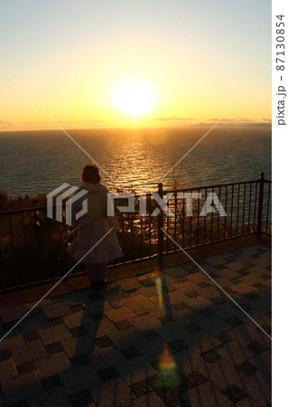 海の夕陽を見る女性のシルエット 87130854