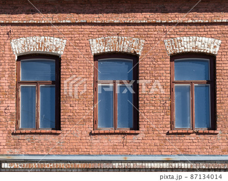 Three windows of the old mansion 19 century with brown bricks wall Three windows of the old mansion 19 century with brown bricks wall 87134014