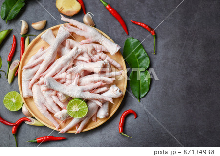 Chicken feet on wooden plate with herbs and spices lemon chili garlic kaffir lime leaves, Fresh raw chicken feet for cooked food soup on the dark table kitchen background 87134938