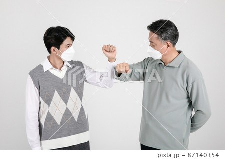 asian korean old and young two men wearing a mask elbow bump asian korean old and young two men wearing a mask elbow bump 87140354
