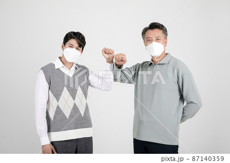 asian korean old and young two men wearing a mask elbow bump 87140359