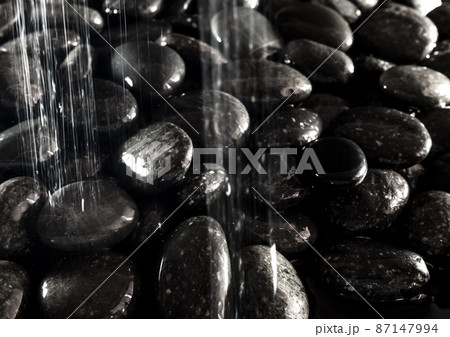 Round black stone on ground beside the waterfall Round black stone on ground beside the waterfall 87147994