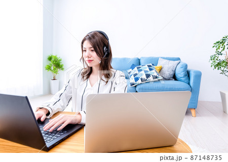 部屋でノートパソコンを操作する笑顔の若い女性 部屋でノートパソコンを操作する笑顔の若い女性 87148735