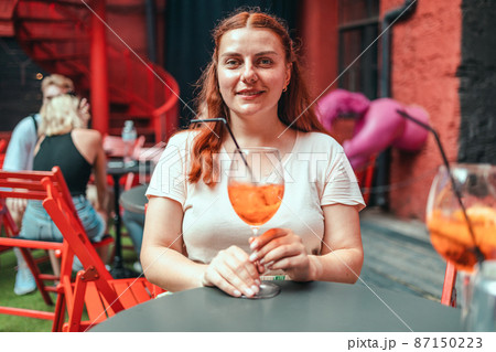 Happy woman drinking classic italian aperitif aperol spritz cocktail. Traditional summer fresh drink Happy woman drinking classic italian aperitif aperol spritz cocktail. Traditional summer fresh drink 87150223