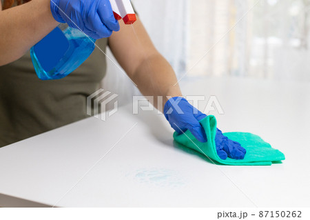 Close up view of woman clean house or restaurant. A girl in rubber gloves wiped the dust with spray and a blue cloth to clean the dirty table. Close up view of woman clean house or restaurant. A girl in rubber gloves wiped the dust with spray and a blue cloth to clean the dirty table. 87150262