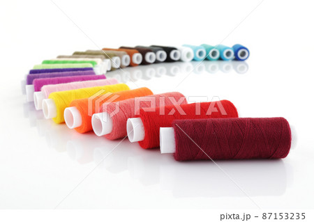 colored cotton reels in an arc on white with shallow depth of field 87153235