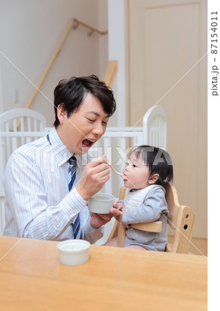 赤ちゃんに離乳食を食べさせる会社員のパパ 赤ちゃんに離乳食を食べさせる会社員のパパ 87154011