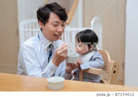 赤ちゃんに離乳食を食べさせる会社員のパパ 87154012