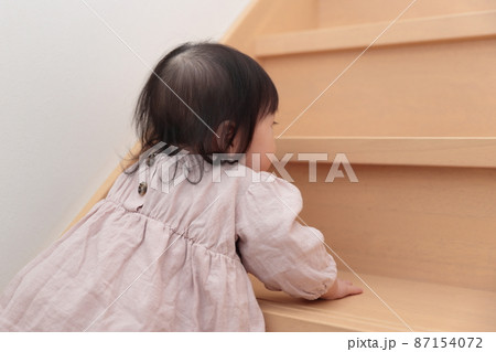 フローリングの階段を登ろうとする0歳の赤ちゃんの女の子 フローリングの階段を登ろうとする0歳の赤ちゃんの女の子 87154072