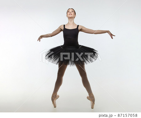 attractive ballerina stands on her fingertips. photo shoot in the studio on a white background attractive ballerina stands on her fingertips. photo shoot in the studio on a white background 87157058