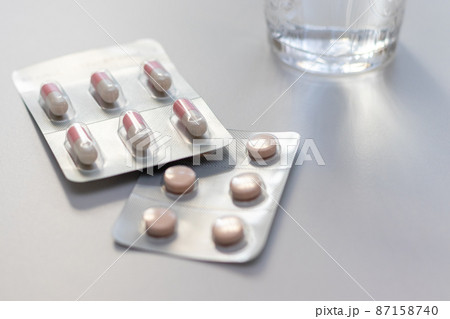 白い机に置かれた飲み薬とコップの水 白い机に置かれた飲み薬とコップの水 87158740