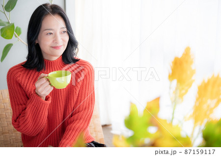 コーヒーを飲みながらくつろぐアジア人（日本人）女性　コピースペースあり　正面	 87159117