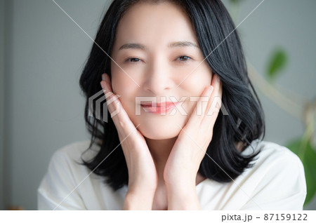 お肌の調子を気にして微笑む美しいアジア人(日本人）女性 クローズアップ　正面　カメラ目線	 87159122