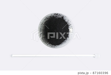 Carbon Charcoal Powder in Chemical Watch Glass placed next to stirring rod. Close up chemical ingredient on white laboratory table. Top View Carbon Charcoal Powder in Chemical Watch Glass placed next to stirring rod. Close up chemical ingredient on white laboratory table. Top View 87160396