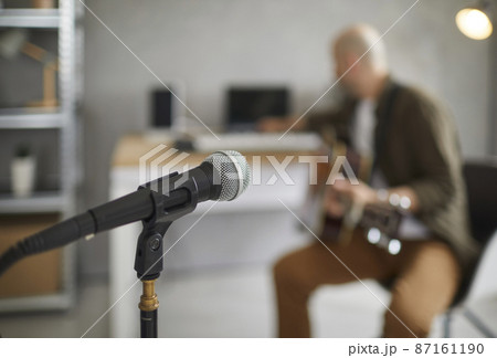 Workplace of singers and musicians. Microphone close up on blurred background of musician in home music rehearsal studio. Concept of musical instruments and devices. Soft focus. Workplace of singers and musicians. Microphone close up on blurred background of musician in home music rehearsal studio. Concept of musical instruments and devices. Soft focus. 87161190
