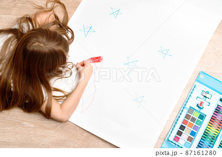 Little boy drawing a picture on the floor in his room, top view. Children's art , home schooling and creativeness concept. High quality photo. Little boy drawing a picture on the floor in his room, top view. Children's art , home schooling and creativeness concept. High quality photo. 87161280