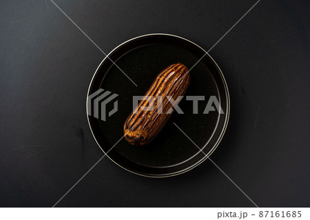 dessert is a small puff pastry pie with stuffing inside on a black serving plate on a black background . A piece of cake with a cut 87161685
