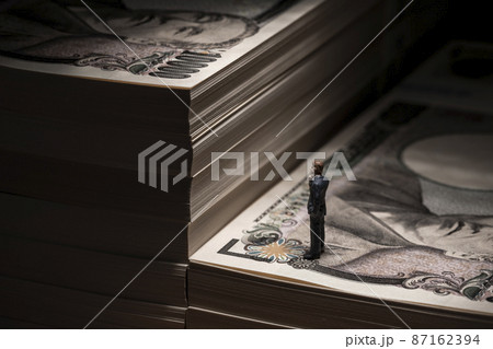 お金（札束）とミニチュアのビジネスマン 87162394