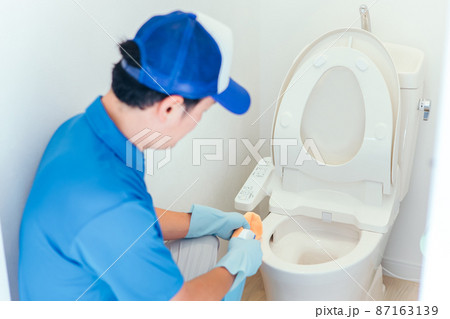 トイレの掃除をする作業着の男性 87163139