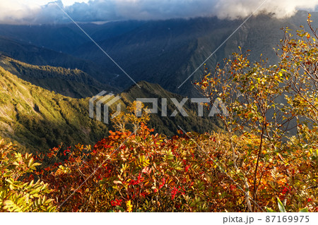 紅葉の谷川岳・西黒尾根から見る朝日差す山並み 87169975