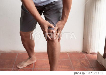A man supporting herself from numbness, muscle weakness, pain, and tingling in the knee nerve endings. This is a side effect of Guillain-Barre Syndrome after vaccination against COVID-19 87171132