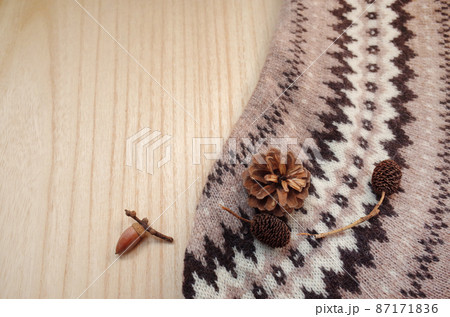 木のテーブルの上にニットと松ぼっくりとドングリとオオバヤシャブシ 87171836