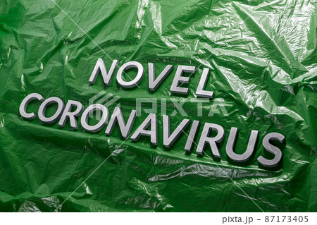 The words novel coronavirus laid with silver metal letters on green crumpled plastic film - diagonal composition The words novel coronavirus laid with silver metal letters on green crumpled plastic film - diagonal composition 87173405