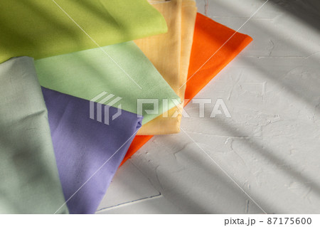 Stack of colorful cotton fabric against grey background, slow fashion and home sewing concept Stack of colorful cotton fabric against grey background, slow fashion and home sewing concept 87175600