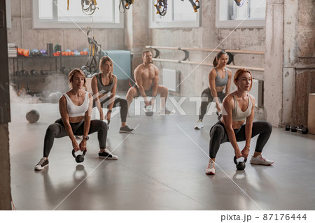 Group of people exercising with kettlebells at gym Group of people exercising with kettlebells at gym 87176444