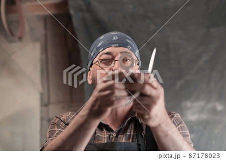 Spoon craft master in his workshop with handmade wooden products and tools working Spoon craft master in his workshop with handmade wooden products and tools working 87178023