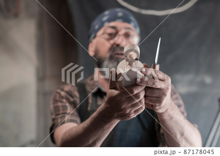 Spoon craft master in his workshop with handmade wooden products and tools working Spoon craft master in his workshop with handmade wooden products and tools working 87178045
