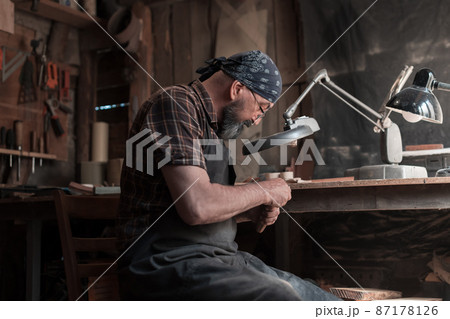 Spoon master in his workshop with wooden products and tools Spoon master in his workshop with wooden products and tools 87178126