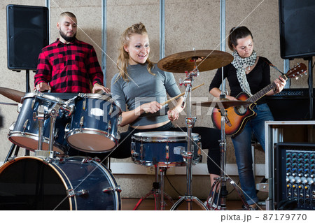 Music band with happy girl drummer rehearsing Music band with happy girl drummer rehearsing 87179770