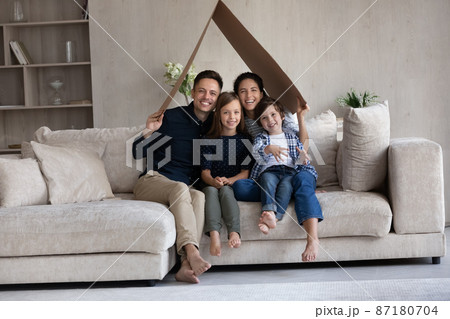 Happy parents and two cute kids holding cardboard paper roof 87180704