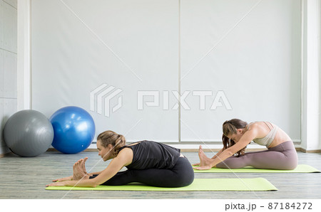 Two young women play yoga stretching, exercise for health in fitness, the concept of physical and mental health care 87184272