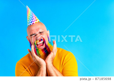 happy man with colorful beard wear horn on head in blue studio background happy man with colorful beard wear horn on head in blue studio background 87185698