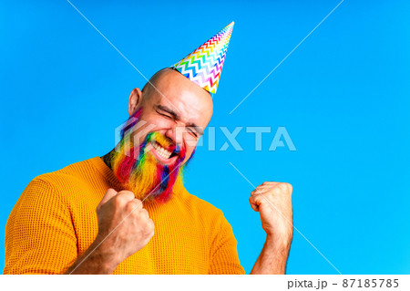 happy man with colorful beard wear horn on head in blue studio background 87185785